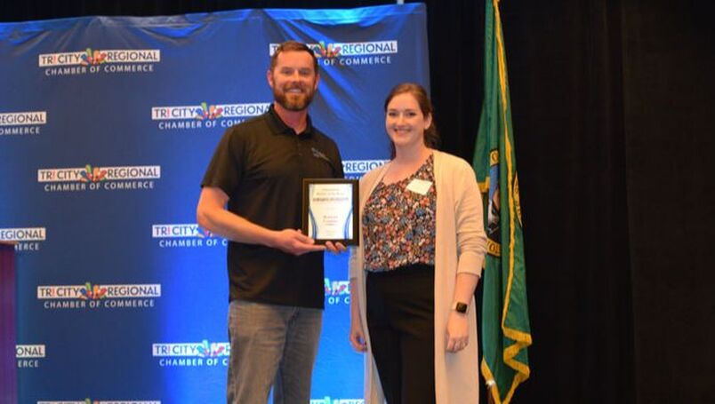 Benton County Commissioner Will McKay and Communications Coordinator Shyanne Palmus accept the award for October Member of the Month