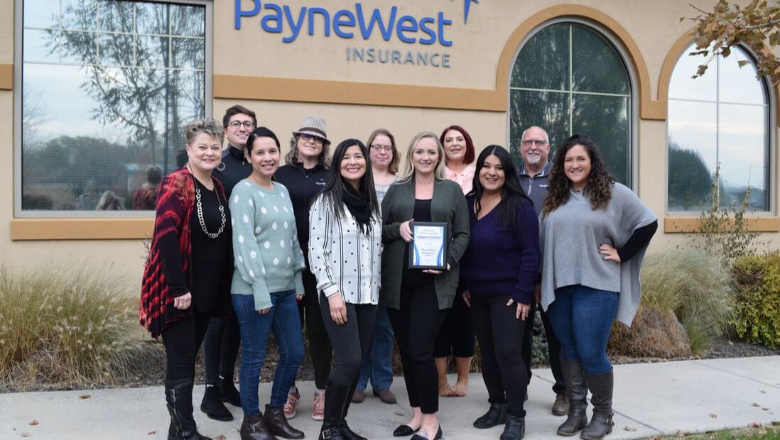 Staff members at PayneWest Insurance pose for a photo with their member of the month plaque